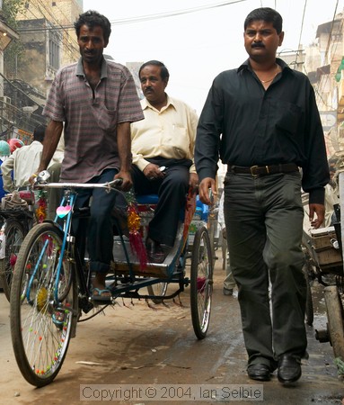 Trishaw driver with passenger, and pedestrian in the street, Old Delhi