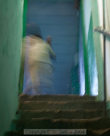 Nizammudin district, Delhi.  A 	child scampers up a dim, but colourful, stairway