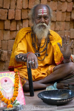 In a narrow street of Old Varanasi a Sadhu has set up on the pavement