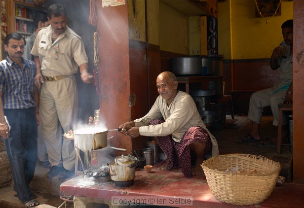Everyday life in the narrow streets of old Varanasi: the old man has let his milk boil over but seems more amused than upset