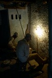 Behind the scenes in old Varanasi the working conditions are not pleasant.   These men work in near darkness grinding small metal components.