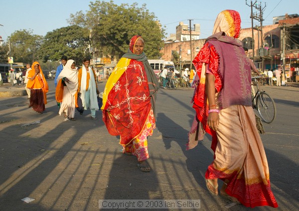 Brightly dressed women cross the street in the early morning, Jaipur