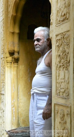 Man looking out  of carved sandstone doorway, Old Delhi