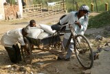 Smiling men pushing a heavy load on a tricycle, Delhi