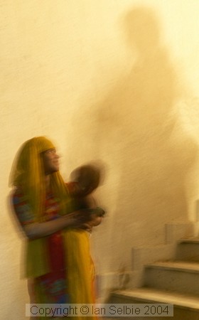 Behind the scenes at the Delhi arts and crafts exhibition, workers are carrying building materials up the shadowy stairway.  The baby came along for the ride.