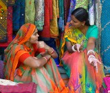 Two sales ladies chatting among their wares at the Janpath Lane textiles market, Delhi