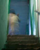 Nizammudin district, Delhi.  A 	child scampers up a dim, but colourful, stairway