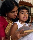 Mother reading to her daughter at celebration of the Full Moon at Sri Senpaga Vinayagar Temple, Ceylon Road, Singapore