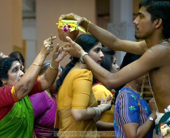 Priest handing ouit milk at celebration of the birthday of Lord Ganesha at Sri Senpaga Vinayagar Temple, Ceylon Road, Singapore