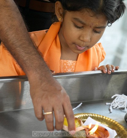 Child watching the lighting of an oil lamp in celebration of the Depavali Festival at Sri Senpaga Vinayagar Temple, Ceylon Road, Singapore