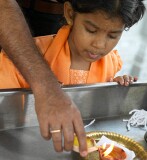 Child watching the lighting of an oil lamp in celebration of the Depavali Festival at Sri Senpaga Vinayagar Temple, Ceylon Road, Singapore
