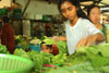 Little boy peeps beneath the hands of the vegetable stall holder