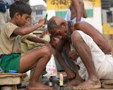 Shaving the heads of children and adults is a symbol of purification before bathing in the Ganges.   Here the children are shaving the elders