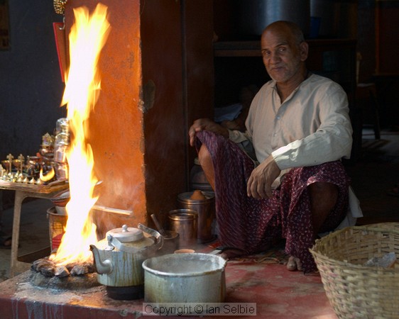 Everyday life in the narrow streets of old Varanasi: the old man has let his milk boil over but seems more amused than upset