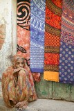 This old woman sits by the textiles on display but seems to be oblivious to passersby and potential buyers