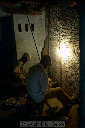 Behind the scenes in old Varanasi the working conditions are not pleasant.   These men work in near darkness grinding small metal components.