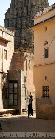 Small boys running through narrow street with Hindu temple in the background, Jaipur